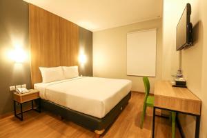 日惹Hotel Citradream Tugu Yogyakarta的一间卧室配有一张床、一张书桌和一台电视