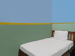 名古屋SPOT ON 92538 Joyoakis Homestay Syariah的蓝色墙壁间的一张床位