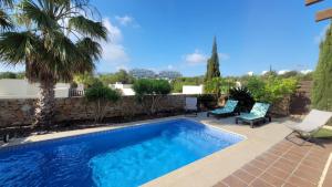 维拉科斯塔Villa Golf Las Colinas的一个带两把椅子的游泳池,一个棕榈树