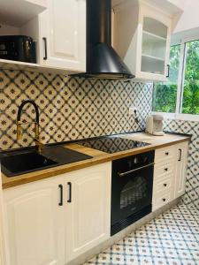瓦伦西亚Marin Beach Apartment Malvarrosa的厨房配有白色橱柜、水槽和炉灶。