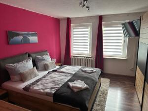 Ferienwohnung, Apartment, Monteurwohnung mit Klimaanlage Wettin - Löbejün的卧室配有一张带粉红色墙壁的大床