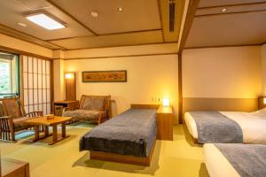 那须盐原市Shionoyu Onsen Rengetsu的酒店客房带两张床和一张桌子以及椅子。