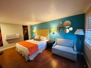 奥兰治Casa Blanca Hotel & Suites Orange SR-55 Freeway, Near Honda Center, Chapman University, Disneyland的配有一张床和一把椅子的酒店客房