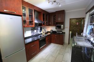 圣卢西亚Pelican's Nest Holiday Home St Lucia的厨房配有木制橱柜和白色冰箱。