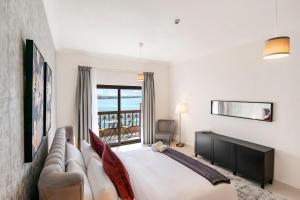 迪拜FAM Living - Sarai Apartments - Private Beachfront Escape in Palm Jumeirah的一间卧室配有一张床、一张沙发和一个窗口