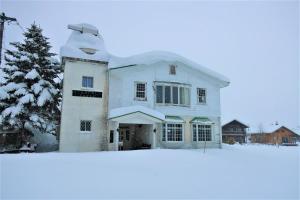 白马村Starfall Lodge的树前的雪覆盖的房子