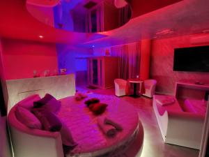 ApricenaB&B Luxury Room & SPA的两个人躺在一间粉红色灯的房间的床上