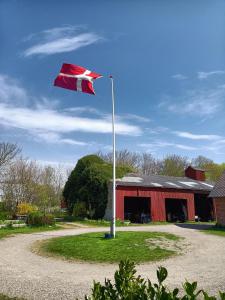 斯凯拜克Fæbrogaard Apartment的红谷仓前的柱子上的旗帜