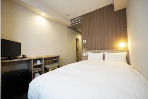 松江市新松江城市酒店的卧室配有一张白色大床和电视。