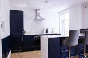 卡迪夫Designer Cardiff Apartments的厨房配有深蓝色橱柜和黑色凳子