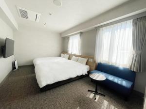 松江市新松江城市酒店的一间卧室配有一张大床和一张蓝色的沙发