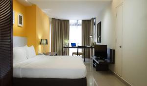 吉隆坡武吉免登华侨城套房公寓式酒店的一间酒店客房,配有一张白色的床和一张书桌