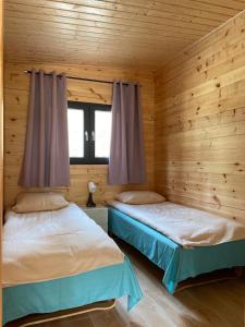 博格泽利卡Toscana Camp的木墙客房的两张床