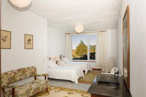 塞哥维亚Hotel Rural Costa del Trigo的白色的客房设有两张床和窗户。