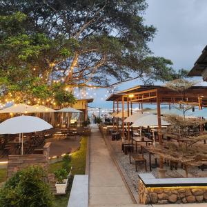 巴利盖Damar Toba的海滩上设有桌子和遮阳伞的餐厅