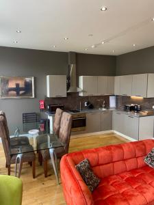 卡斯尔敦Halvard Apartments at Castletown的一间带红色沙发的客厅和一间厨房