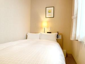 松江市新松江城市酒店的一间卧室配有一张白色的床,上面有灯
