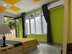 岘港Yên Homestay Đà Nẵng的绿色卧室设有床和窗户