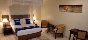 坎帕拉Koki Hotel的酒店客房带一张床、一张桌子和椅子
