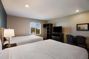 克莱蒙WoodSpring Suites Orlando West - Clermont的酒店客房设有两张床和电视。