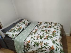 埃德蒙顿Nice Studio Flat in Edmonton, North London的一张带花卉棉被的床和两个枕头