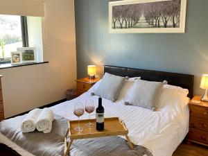LlangunlloOak View Cottage的一间卧室配有一张带两杯葡萄酒的床