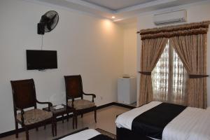 锡亚尔科特Hotel de Raj Sialkot的一间卧室配有一张床、两把椅子和电视