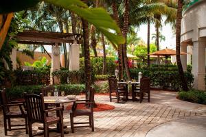 达尼亚滩Courtyard by Marriott Fort Lauderdale Airport & Cruise Port的一个带桌椅和棕榈树的庭院