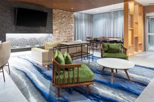 玛丽埃塔市Fairfield Inn & Suites by Marriott Atlanta Marietta的酒店大堂设有桌椅和电视。