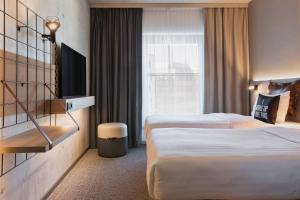 汉堡Moxy Hamburg City的酒店客房设有两张床和窗户。