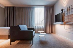 美因河畔法兰克福Moxy Frankfurt City Center的配有床、椅子和桌子的酒店客房