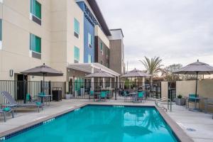 默塞德TownePlace Suites by Marriott Merced的游泳池,配有桌椅和遮阳伞
