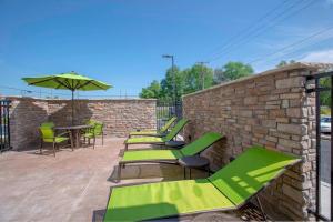 纽瓦克Springhill Suites By Marriott Newark Downtown的一个带绿色桌椅的庭院和砖墙