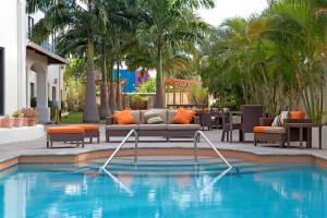 西班牙港西班牙万豪万怡酒店的一个带沙发和椅子的游泳池以及棕榈树