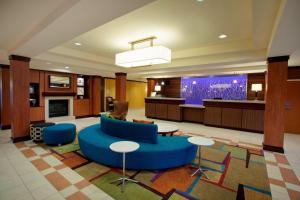 罗缪勒斯Fairfield Inn & Suites by Marriott Detroit Metro Airport Romulus的大堂设有蓝色的沙发、桌子和电视。