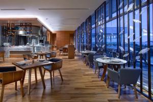 哥打京那巴鲁哥打京那巴鲁万豪酒店&度假村的餐厅设有桌椅和大窗户。
