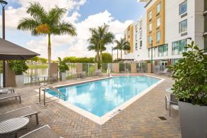 肯代尔TownePlace Suites Miami Kendall West的一个带庭院家具和棕榈树的游泳池
