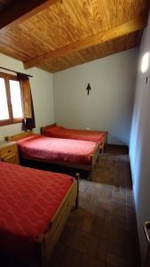 塔菲德尔瓦勒Casa en Tafí del Valle的配有红色床单和木制天花板的客房内的两张床