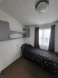 海斯廷斯Haven Dreams Caravan的一间小卧室,配有一张黑色的床和一个窗户