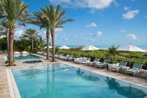 迈阿密海滩斯坦顿南海滩万豪酒店的度假村的游泳池,种植了棕榈树,配有椅子