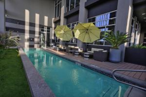 墨西卡利Fairfield Inn & Suites by Marriott Mexicali的酒店设有带遮阳伞和椅子的游泳池