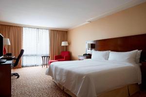 斯坦福德斯坦福万豪水疗酒店的酒店客房设有一张大床和一张红色椅子。