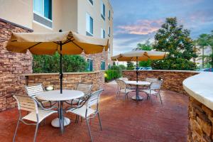 塔拉哈西塔拉哈西中心费尔菲尔德万豪套房酒店的一个带桌椅和遮阳伞的庭院。