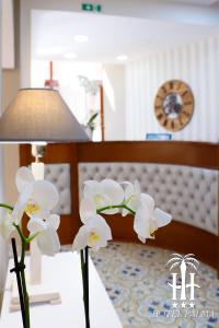 卡斯特拉玛雷帝斯达比亚Hotel Palma的睡床旁的花瓶,满是白色的花