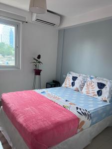 宿务Cebu Mini Hotel的一间卧室配有一张带粉色毯子的床和窗户。