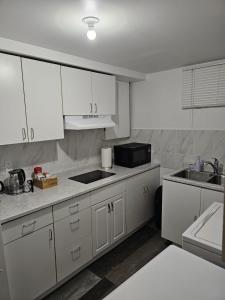 温尼伯River Park South - 2 Bedroom Basement Suite的厨房配有白色橱柜、水槽和微波炉