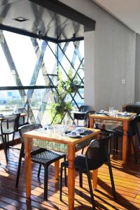 戈亚尼亚Hotel Black Inn Flamboyant的餐厅设有木桌、椅子和大窗户。