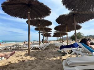 马力诺港Villas Yanina Luxe Gran Alacant的海滩上的一组椅子和遮阳伞