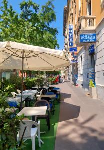 米兰Hotel Aurelia Milano Centrale的室外咖啡厅配有桌椅和遮阳伞