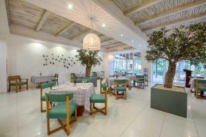 蓬塔卡纳Grand Sirenis Punta Cana Resort & Aquagames - All Inclusive的一间设有桌椅和树木的餐厅